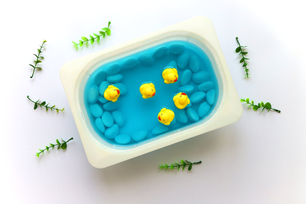 Five rubber ducks floating in a tray filled with water, demonstrating an activity to promote physical development in children