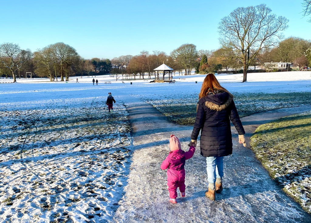 Mother and daughter walking through a park on a winter scavenger hunt 