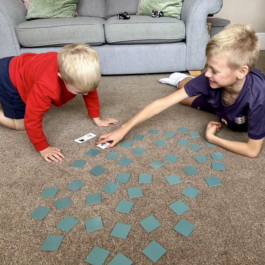 Two children play initial sound match on the floor